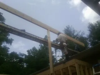 Carpenter setting a ridge beam over a new addition frame — Ice Dam Removal by Roofing Brothers in Moncure