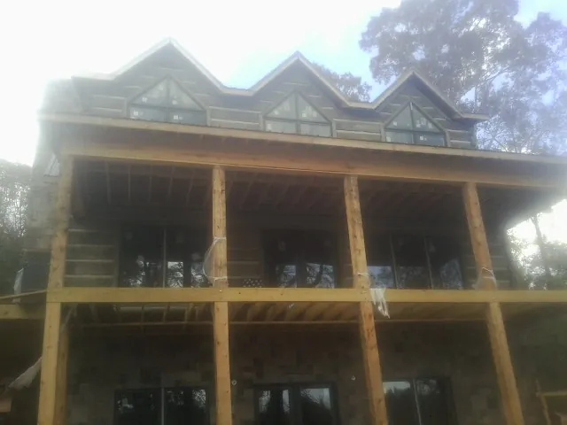 Dormers and porch framing on a large log home under construction — Roof Coating work by our crew in Moncure