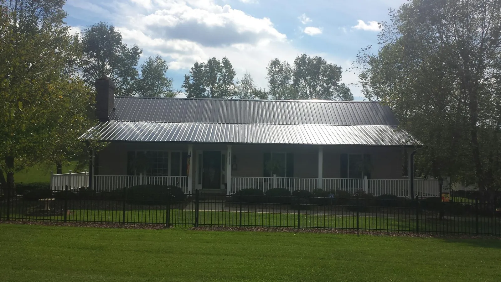 Gray metal roof on a brick ranch with a full width front porch — Gutter Guard Installation work by our crew in Moncure