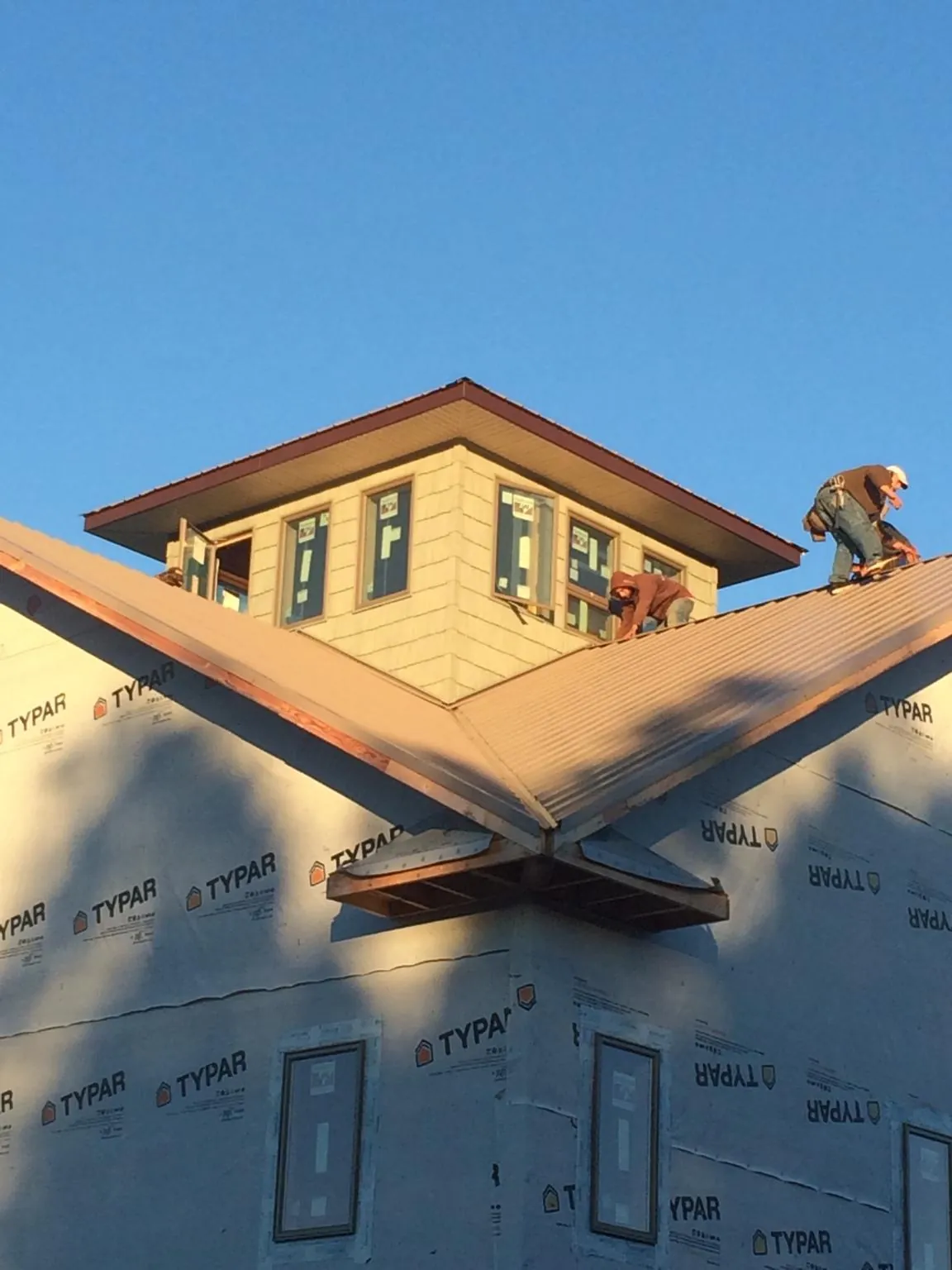 Roofers working around a rooftop cupola on a new metal roof at sunset — Roof Waterproofing in Moncure by Roofing Brothers